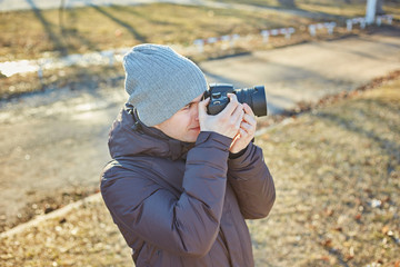 photographer in a hat, makes a photo on his camera in the winter park