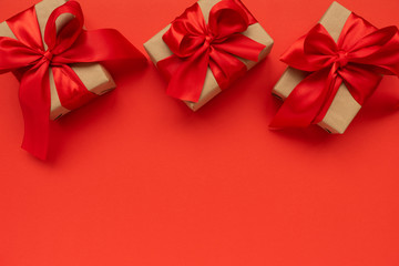 Three gift boxes wrapped on red ribbons on red background. Valentines day or Mothers day celebration concept. Top view. copy space