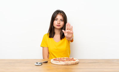 Caucasian girl with a pizza making stop gesture with her hand