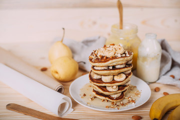 Stack of delicious pancakes with honey, nuts and slices of banana.