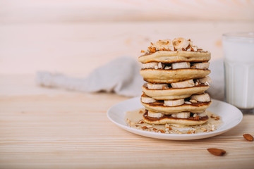 Stack of delicious pancakes with honey, nuts and slices of banana.