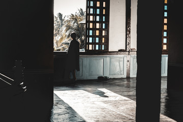 Old wooden Filipino house with woman staring outsude on Spanish style stained glass window