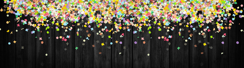Carnival background panorama banner long - Colorful confetti isolated on rustic black wooden texture, with space for text