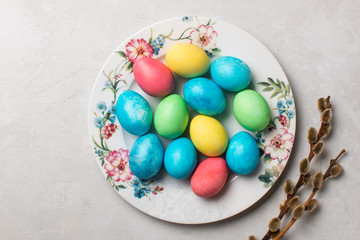 Colorful easter eggs in a beautiful plate on a gray background