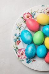 Colorful easter eggs in a beautiful plate on a gray background