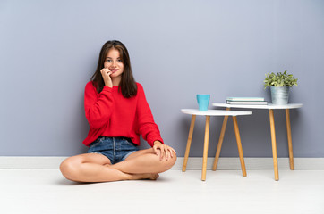 Young woman sitting on the floor nervous and scared