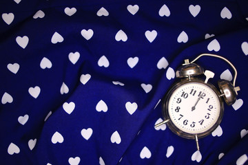 Retro alarm clock on a blue background with white hearts. Classic blue. Deadline concept. 