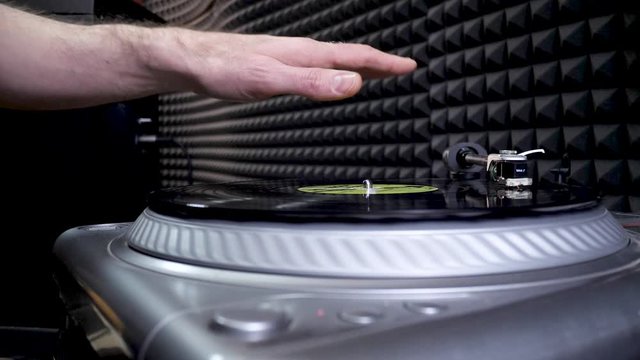 DJ Mixing and Scratching vinyl disc in professional record studio. Hands tweak various track controls on dj's deck