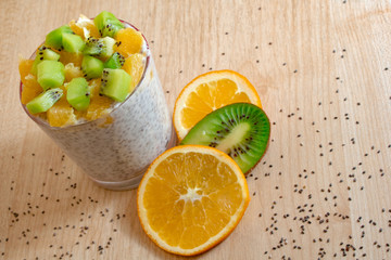 Fototapeta na wymiar healthy breakfast of chia seeds of orange and kiwi yogurt on a wooden background fitness food. copy space