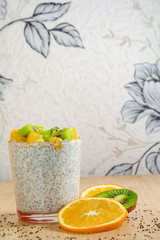 healthy breakfast of chia seeds of orange and kiwi yogurt on a wooden background fitness food. copy space