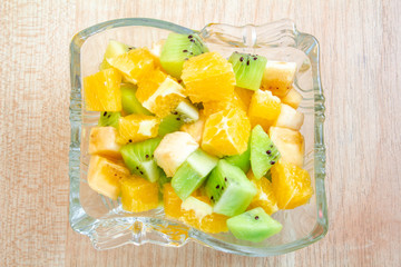 healthy breakfast salad of orange banana and kiwi in a glass dish on a wooden background fitness food. copy space