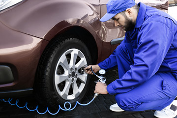 Mechanic checking tire air pressure at car service