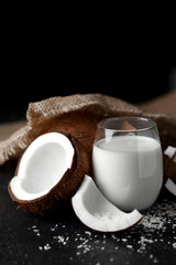 fresh coconut milk in a glass against a dark background, coconut cosmetic cream, milkshake with coconut slices