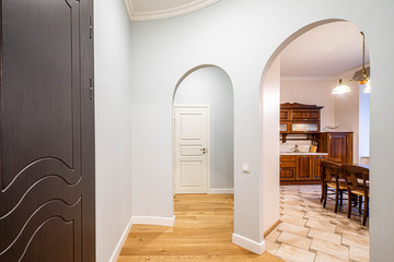 Entrance hall in modern apartment. Interior in light tones. Archs. Kitchen.