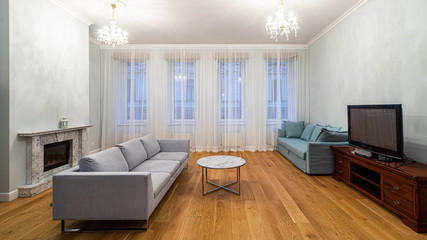 Living room with furniture and fireplace in apartment. Modern interior in light tones.