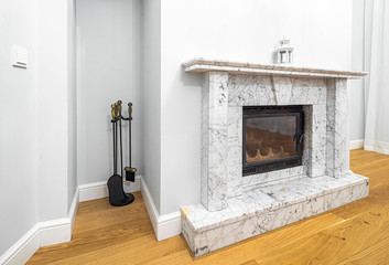 Close-up of fireplace. White walls. Wooden floor. Living room. Luxury apartment.