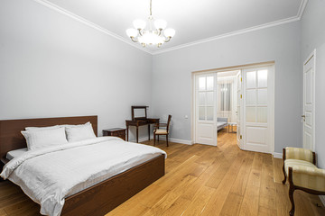 Fototapeta na wymiar Modern interior in light tones. Bedroom with wooden furniture. White door.
