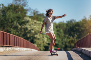 Sporty woman riding on the skateboard on the road. Longboarding, female.