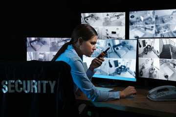 Security guard with portable transmitter monitoring modern CCTV cameras at night