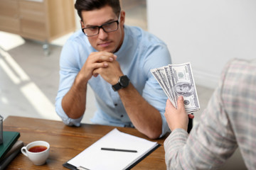 Woman offering bribe money to man at table