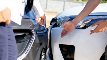 Insurance agents inspect for damage to cars that collide on the road to claim compensation from driving accidents, Insurance concept.