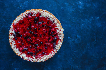 homemade pie tart with berry jelly sliced peanuts on dark blue background top view copy space