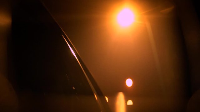 City street lights in side mirror of moving car at night, close up