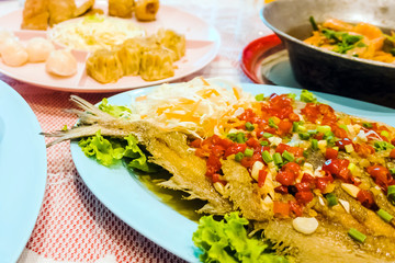 Fried fish and topped with chili sauce along with other types of food placed on the dinner table at parties. Selective focus.