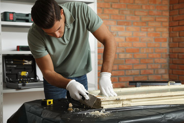 Man repairing old damaged window at table indoors