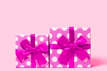Two present boxes with dots  wrapped with bright ribbon on colorful background. Festive and holiday theme.