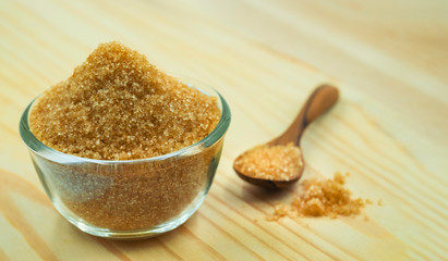 Close-up of Brown cane sugar in glass bowl on wooden table and wooden spoon, pile brown sugar. Raw natural, Organic cane sugar for healthy with copy space for text