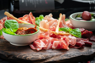 Italian meat appetizers and on a wooden plate. Wine snack Antipasto-salami, prosciutto, slices ham, beef jerky and bread sticks.