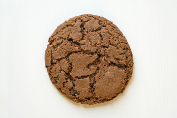 Oaten chocolate cookie on white wooden background