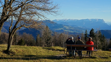Elderly people sit on a bench in the mountains and admire the alpine landscape, Salzburg, Austria.