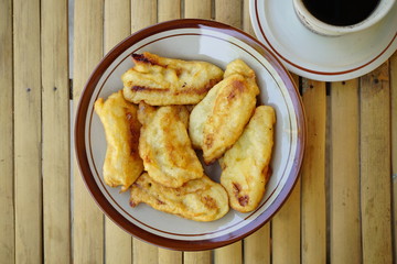 Fried bananas with a glass of coffee on a bamboo table