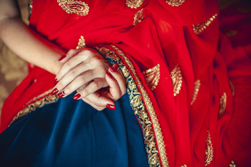 Fototapeta na wymiar hands with red manicure on a red-blue sari