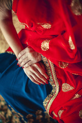 Fototapeta na wymiar hands with red manicure on a red-blue sari