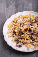 muesli with nuts and dry figs on dish on ceramic background