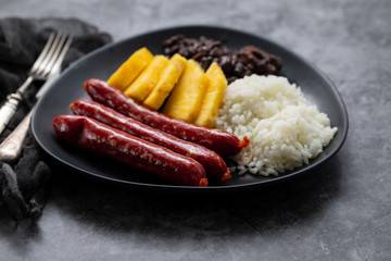 sausages with rice, black beans, and pineapple on dark dish