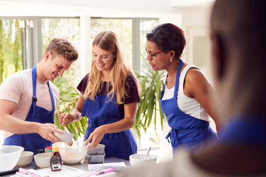 Male And Female Adult Students Measuring Ingredients In Cookery Class In Kitchen