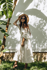 stylish young attractive woman dressed in a long linen dress with a hat photographed in the summer...