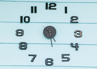 Wall clock with black numbers on a blue wooden background