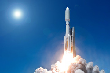 Take off space rocket on a background of blue sky and sun. Elements of this image were furnished by...