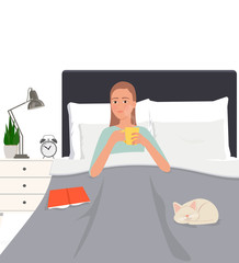 A young girl drinking a hot drink in bed.