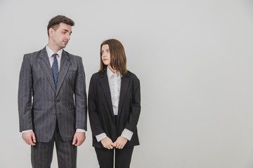 Confident businesspeople wearing office suits, standing, looking at one another.