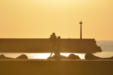 夕暮れの海岸を散歩する家族 © Shoji