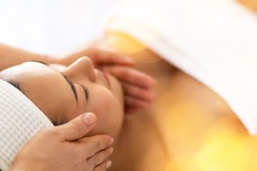 Health & Wellness Retreats concept. Beauty treatment concept Young beautiful Asian Thai woman liing on bed for facial and head massage spa treatment by Masseur. relaxing with closed eyes