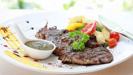 Closeup premium quality Beef Steak with black pepper sauce and vegetables in white plate and knife on the wooden table background. Foods concept.