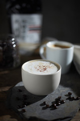 Hot coffee cup and coffee beans on wooden table..