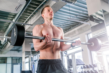 sport, bodybuilding, lifestyle and people concept - young man with barbell flexing muscles in gym